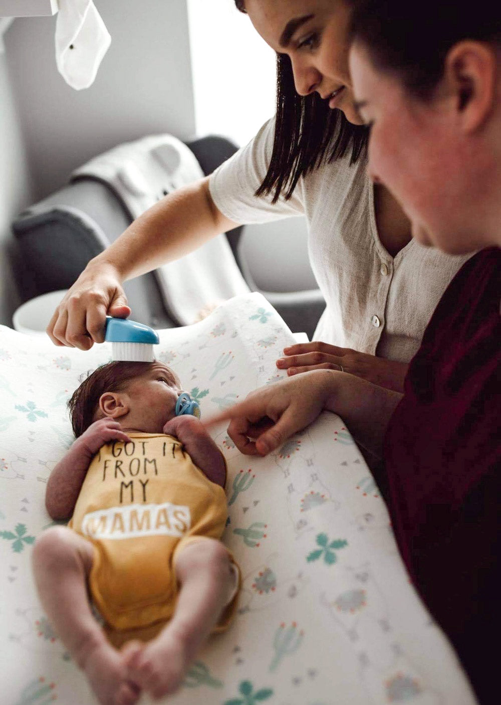 Moms look lovingly down and brush newborn baby boy's hair 
