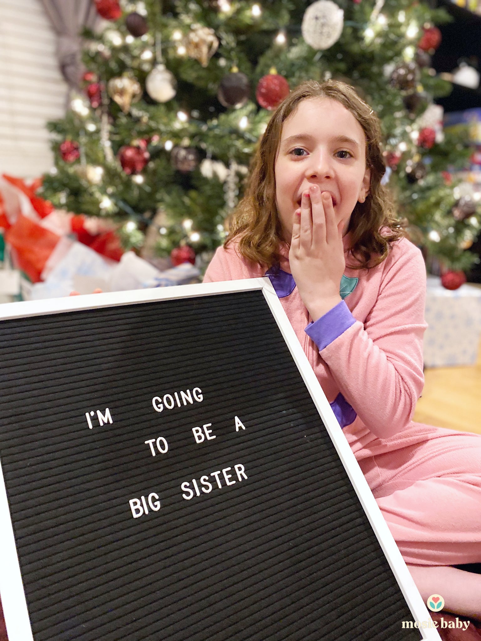 a little girl with a sign "I'm going to be a big sister"
